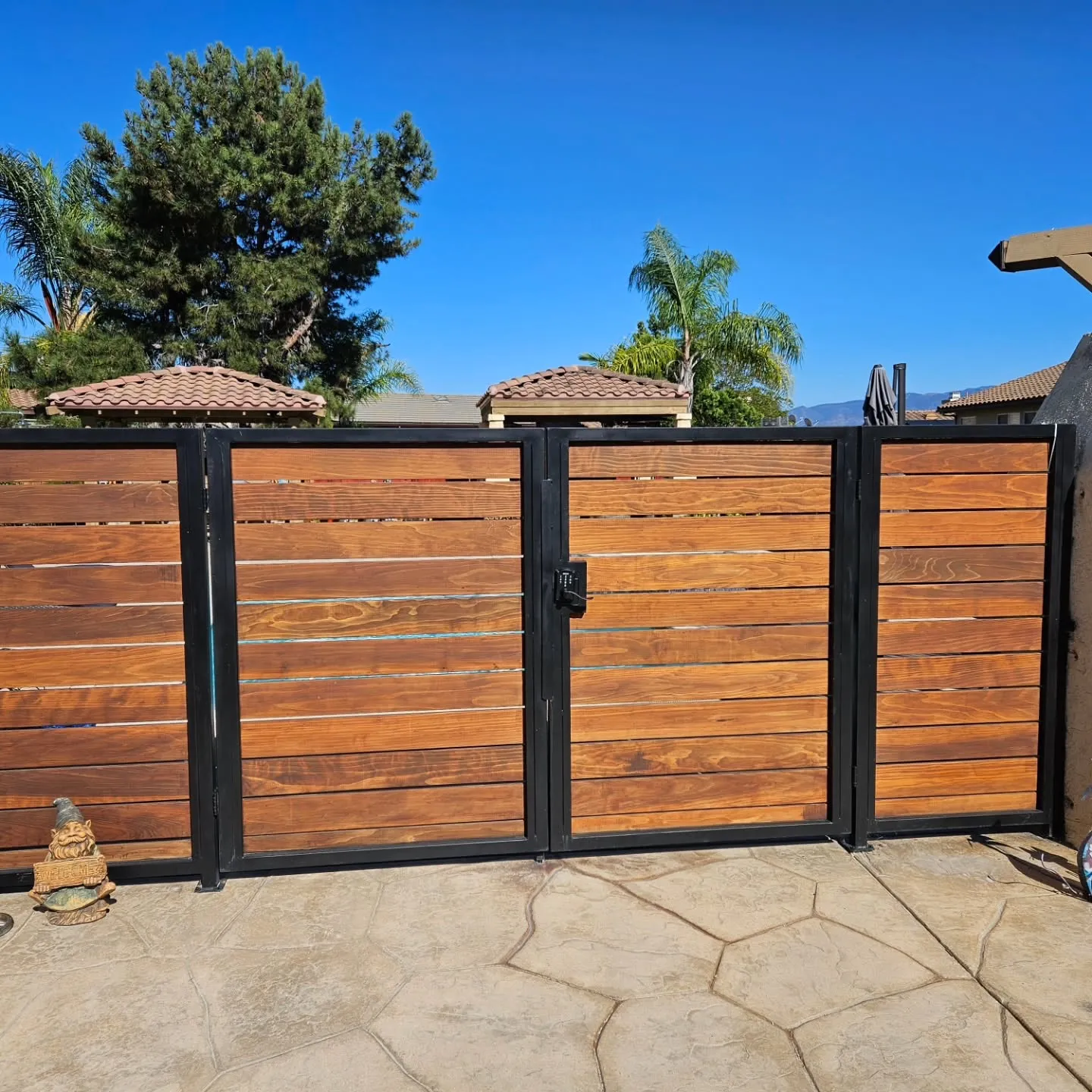 Stained cedar and black steel driveway gate built by Republic Doors and Gates
